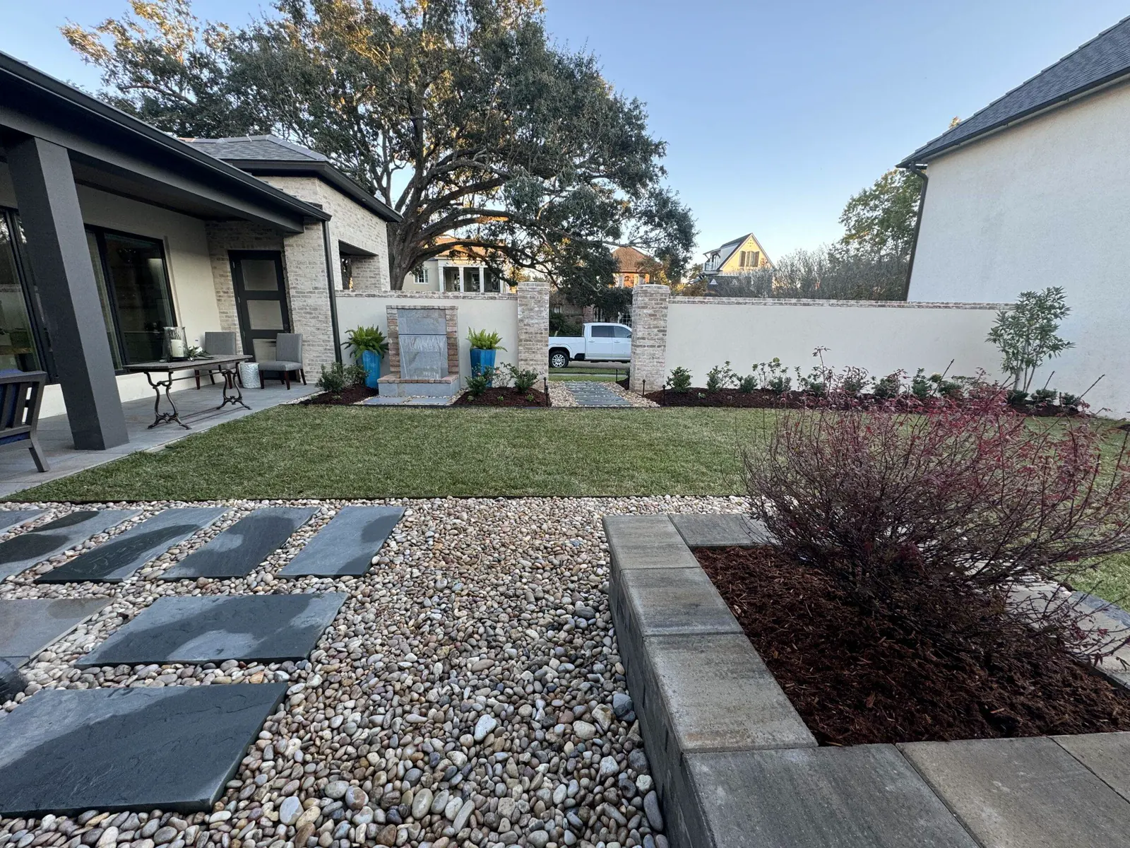 Wide aerial of a backyard with artificial turf, a patio, and a covered seating area
